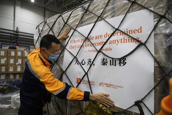 一名戴着口罩的男子正在搬运一托盘运往非洲的人道主义援助物资。这些物资包装上印有纳尔逊·曼德拉的名言以及马云公益基金会和阿里巴巴公益基金会的标志。