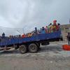Refugiados de Sudán sentados en la parte trasera de un camión azul en el cruce fronterizo de Metema con Etiopía.
