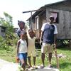A family stands outside their home damaged by Hurricane Beryl in St. Andrews, Grenada.