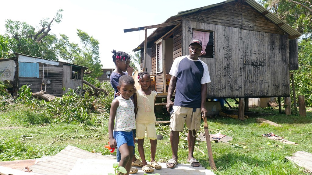 عائلة تقف خارج منزلها المدمر بسبب إعصار بيريل في سانت أندروز، غرينادا.