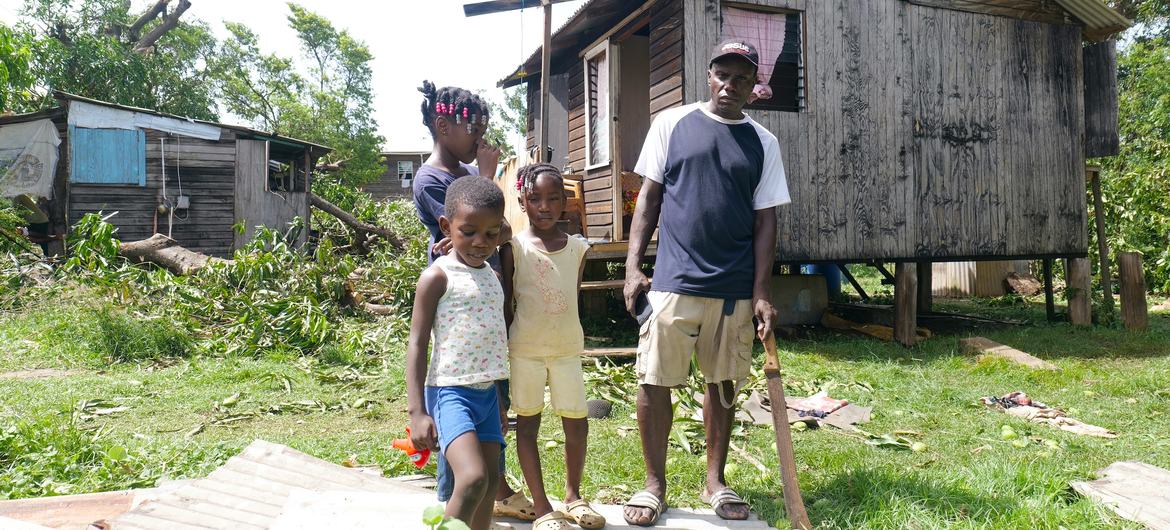 A family stands outside their home damaged by Hurricane Beryl in St. Andrews, Grenada.