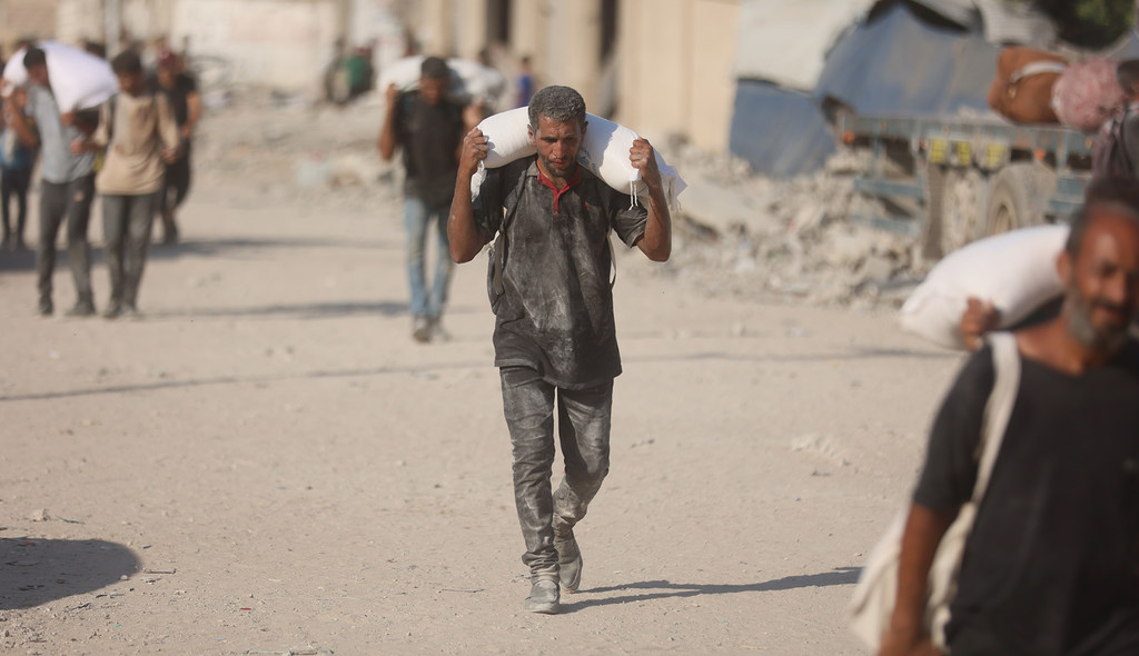 Un homme porte un sac de farine à Gaza.