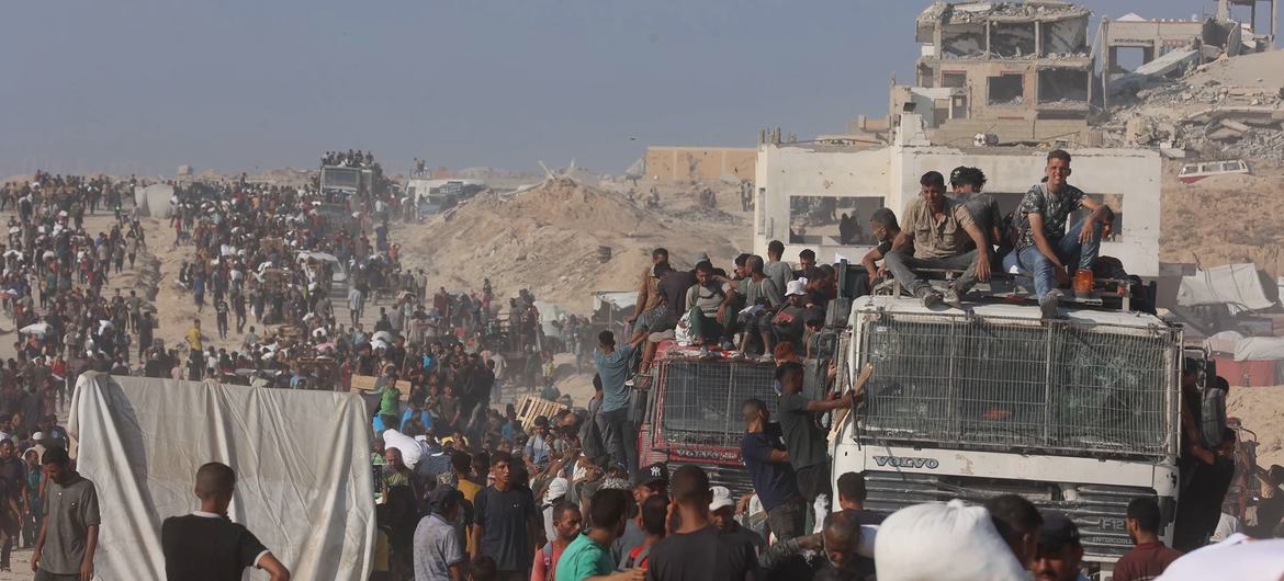 Палестинцы забираются на грузовики гуманитарных агентств, возвращающиеся из северной части Газы.