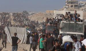 Palestinos abordan camiones de ayuda que regresan del norte de Gaza.