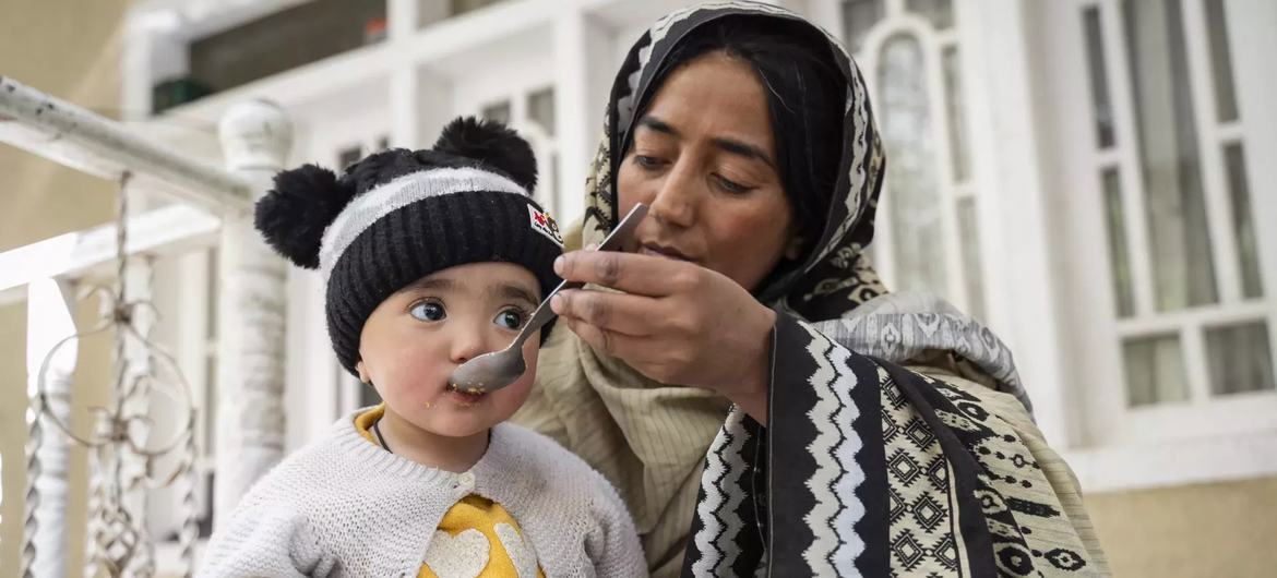 Uma agente comunitária de saúde alimenta uma criança pequena em uma área rural de Gilgit-Baltistão, no Paquistão.