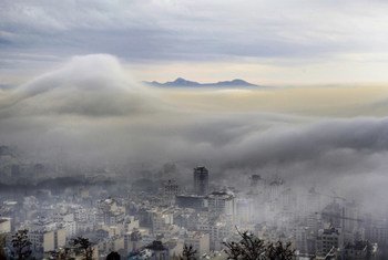 Vista da cidade de Teerã, Irã, a partir de Velenjak, com neblina densa e nuvens obscurecendo os prédios mais baixos e as montanhas ao longe.