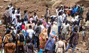 People gather after a landslide destroyed Tarseen village in South Darfur, Sudan.