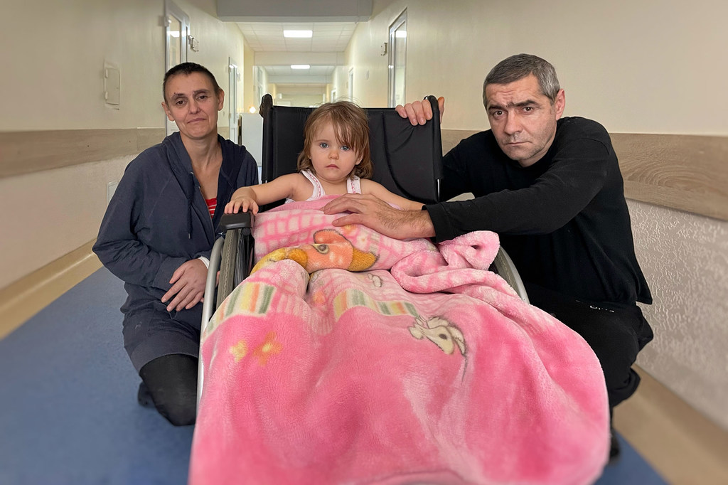 Lisa, una niña de dos años, en silla de ruedas con sus padres en un centro de rehabilitación en Lviv, Ucrania.