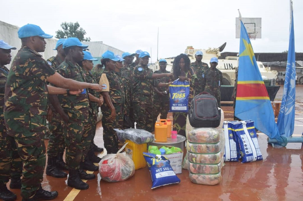 Walinda amani wa Tanzania kutoka TANZBATT-11, sehemu ya ujumbe wa MONUSCO nchini DRC, wanasambaza vifurushi vya misaada kwa mwanamke mwenye yatima. Bendera ya Kongo na bendera UN vinaonekana nyuma.