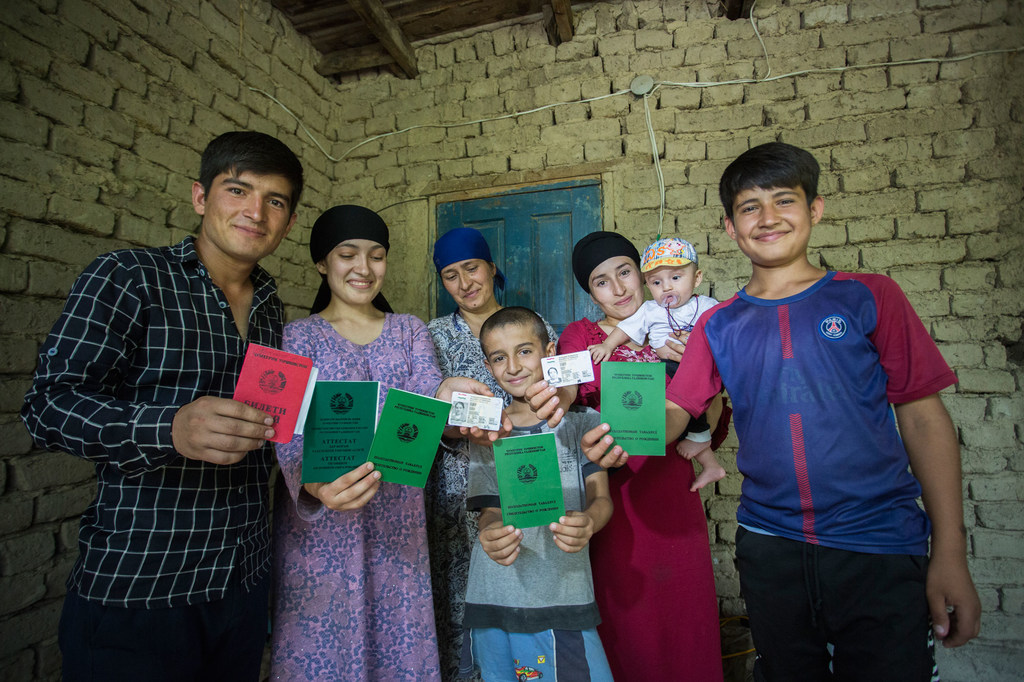 Una familia en Tayikistán sostiene sus documentos de identidad recién obtenidos dentro de su hogar.