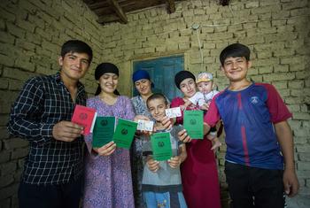 أفراد عائلة- عديمة الجنسية سابقا- يعرضون وثائق الهوية التي حصلوا عليها حديثا في منزلهم في دوشانبي، طاجيكستان.