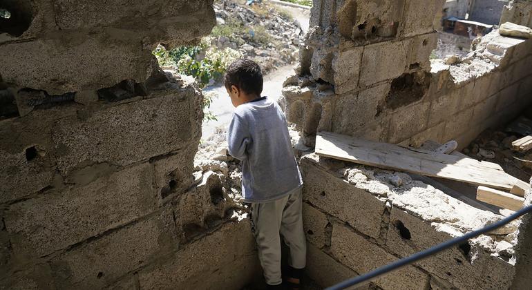 यमन के एक युद्ध प्रभावित इलाक़े में, एक बच्चा अपने क्षतिग्रस्त घर से बाहर की तरफ़ देखता हुआ.