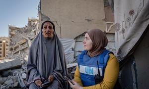 Una trabajadora del PMA habla con una mujer desplazada frente a su casa en Hamad City, Gaza.