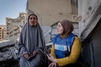 Una trabajadora del PMA habla con una mujer desplazada frente a su casa en Hamad City, Gaza.