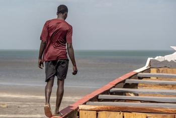 Kijana akitembea juu ya mashua karibu na pwani ya Gambia, eneo ambako mamia ya wahamiaji huanza safari zisizo na uhakika kuvuka bahari kila mwaka.