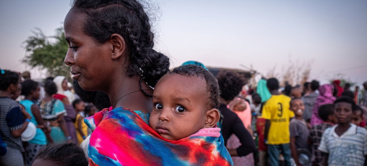 لاجئة من تيغراي تنتظر في صف مع طفلها لتلقي الطعام في مخيم أم راكوبة للاجئين في السودان.
