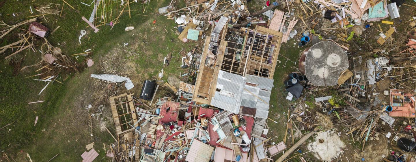 Uma vista aérea de uma área devastada na Jamaica após o furacão Melissa, mostrando casas destruídas e detritos espalhados.
