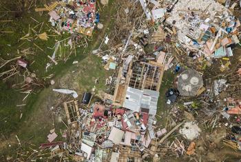 Uma vista aérea de uma área devastada na Jamaica após o furacão Melissa, mostrando casas destruídas e detritos espalhados.