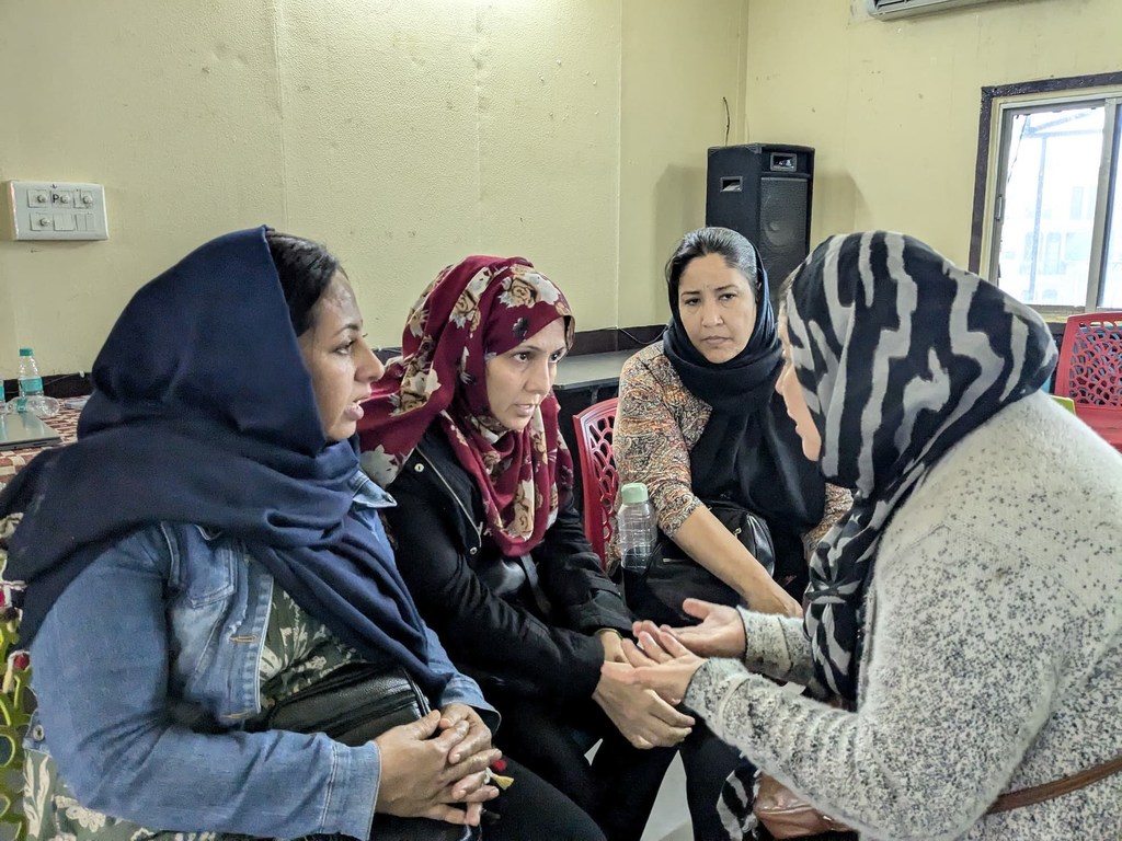 भारत में शरणार्थी महिलाएं एक सहायता समूह में अपनी कहानियां साझा करती हैं और सुरक्षा पर चर्चा करती हैं।