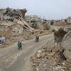 Sur le chemin du retour de l'école, des enfants marchent devant des ruines en Syrie.