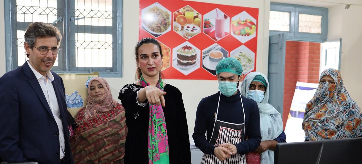ملتان، پاکستان میں ایک پیشہ ورانہ تربیتی باورچی خانے میں لوگوں کا ایک گروپ، جس میں سوٹ میں ایک مرد اور روایتی لباس اور تہبند میں کئی خواتین شامل ہیں۔