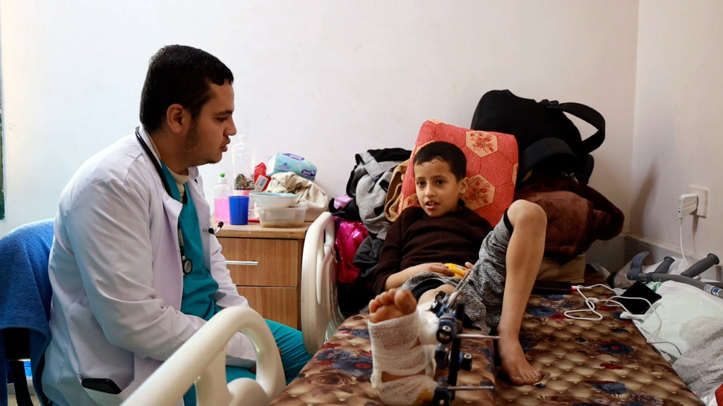 来自加沙的阿卜杜勒拉哈曼医生在舒哈达·埃拉克萨医院与一名受伤的儿童交谈。