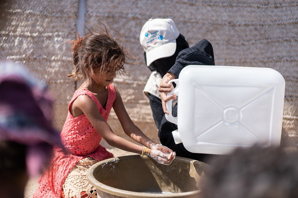 Au Yémen, Yaqoot Saleh, une volontaire de la Fondation Taybah, aide une enfant d'un camp, dans le gouvernorat d'Hodeïda, à se laver correctement les mains avec du savon fourni par l'UNICEF et ses partenaires.