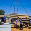 Wafanyakazi katika kituo cha Farchana IOM huko Chad wakishusha paneli kubwa ya chuma kutoka kwa lori kama sehemu ya mradi wa upanuzi wa kukabiliana na migogoro ya Sudan.