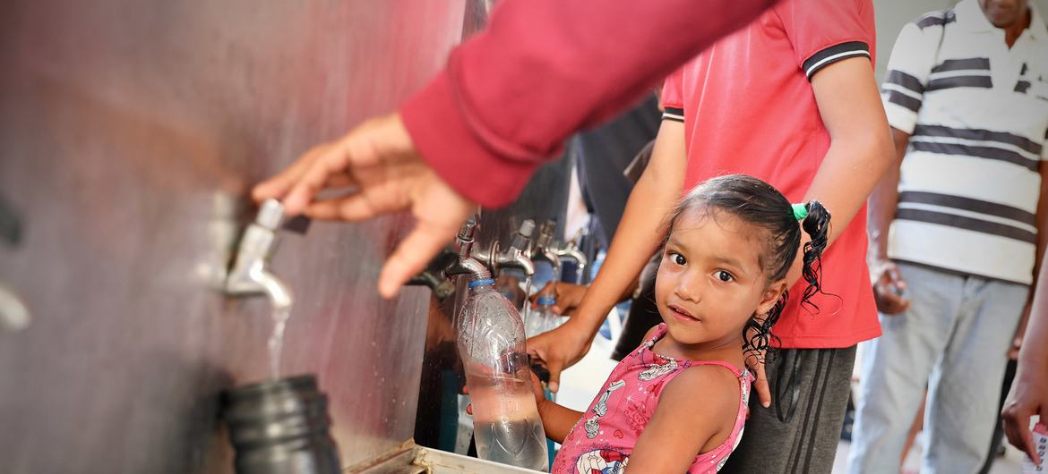 Una muchacha venezolana recibe agua potable en un centro de alojamiento temporal. Foto: OIM/Gema Cortes