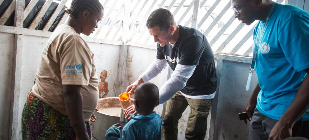 Goodwill Ambassador Orlando Bloom serves porridge at a UNICEF-supported nutrition centre in the Bushagara site for internally displaced people in eastern Democratic Republic of the Congo.