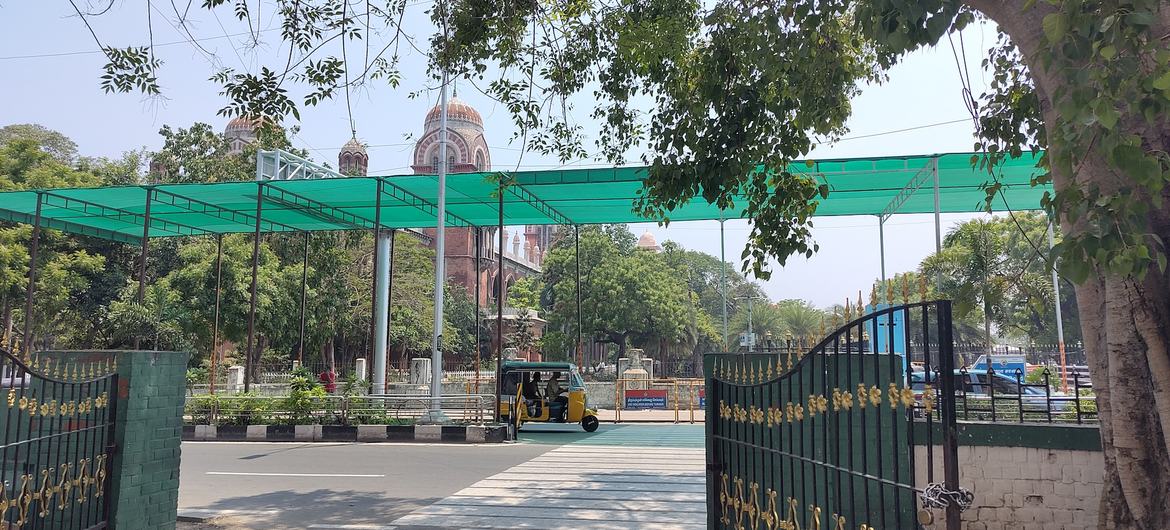 भारत के चेन्नई शहर में एक गुंबददार औपनिवेशिक शैली की इमारत के सामने सड़क को हरे रंग की छायादार चंदवा से ढका गया है, जिसके नीचे से एक ऑटो रिक्शा गुजर रहा है।