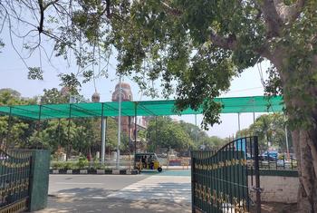 भारत के चेन्नई शहर में एक गुंबददार औपनिवेशिक शैली की इमारत के सामने सड़क को हरे रंग की छायादार चंदवा से ढका गया है, जिसके नीचे से एक ऑटो रिक्शा गुजर रहा है।