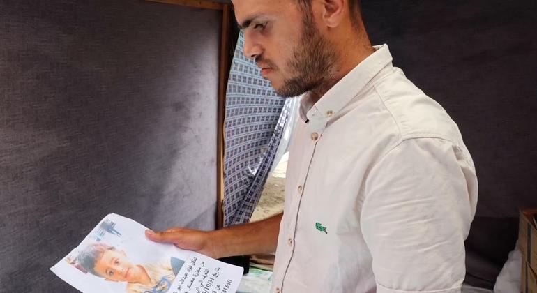 عبدالله أبو القمصان ينظر إلى ملصق عليه صورة ابنه فؤاد، الذي فقد أثره بعد إصابته في تشرين الأول/أكتوبر 2023 بعد قصف بمخيم جباليا للاجئين في غزة.
