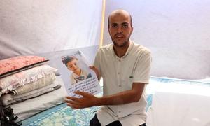Abdullah Abu Al-Qumsan holds a poster with a picture of his son Fouad, who went missing  in October 2023 strike in Jabalia refugee camp in Gaza.