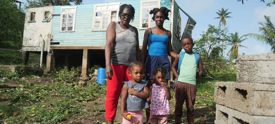 A family stands outside their home destroyed by Hurricane Beryl in Grenada.