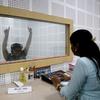 Uma mulher realiza uma avaliação auditiva em um paciente dentro de uma cabine à prova de som no Departamento de Audiologia e Fonoaudiologia.