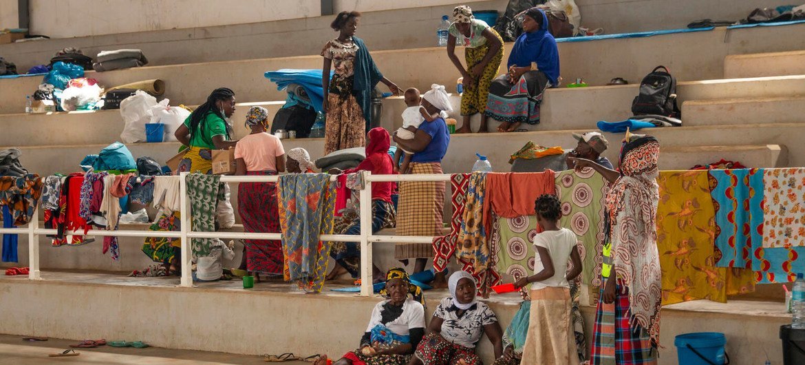 Pessoas deslocadas, incluindo mulheres e crianças, estão no Centro Esportivo de Pemba, em Moçambique, após receberem distribuição de alimentos do Unicef e da parceira AVSI.