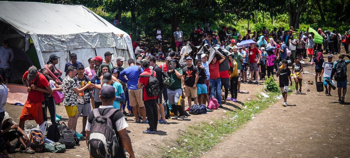 Migrantes hacen fila en un centro de recepción temporal después de cruzar la selva del Darién.