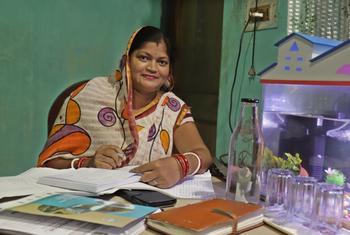 भारतीय महिला चमेली दस्तावेजों और नोटबुक के साथ एक डेस्क पर बैठी है।