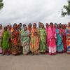 ओडिशा के ग्रामीण इलाके में रंग-बिरंगी पारंपरिक साड़ियों में सजी भारतीय महिलाओं का एक समूह खेत में खड़ा है।