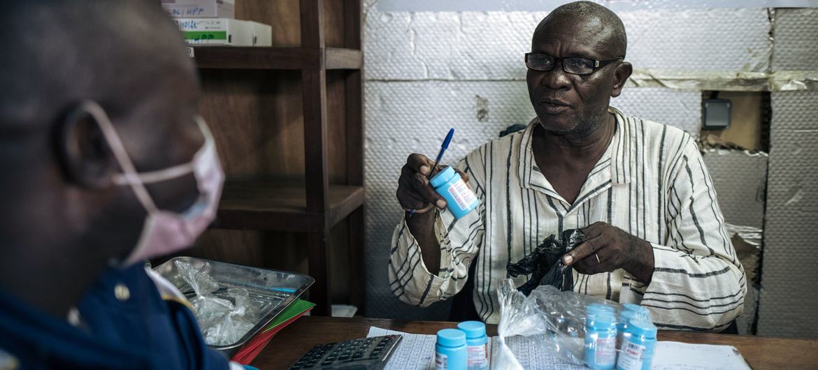 Un distributeur communautaire polyvalent délivre son traitement à un patient au Poste de distribution des ARV pour patients stable (PODI) de la commune de Lingwala à Kinshasa, RDC.