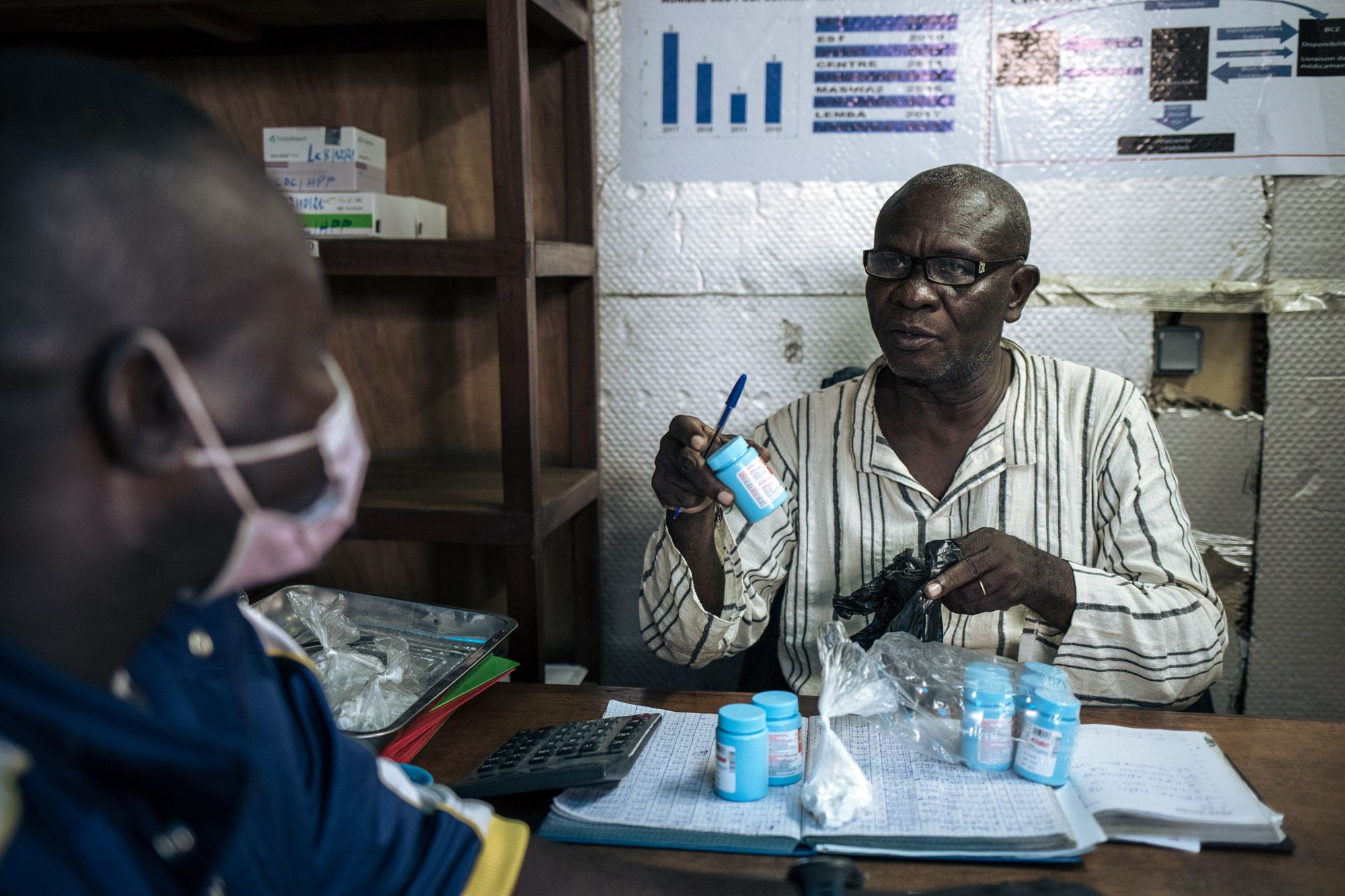 Un distributeur communautaire délivre un traitement antirétroviral à un patient à Kinshasa, en RDC.