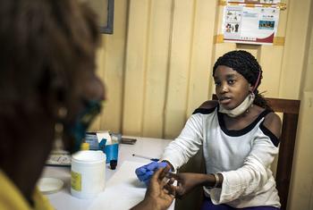 Une conseillère effectue un test rapide de VIH dans un poste de distribution de traitements pour patients stables de la commune de Lingwala à Kinshasa.