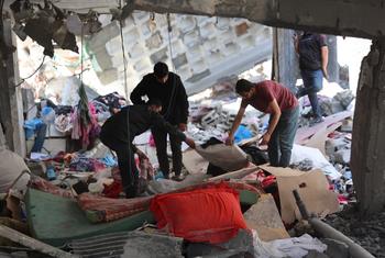 Жители Рафаха ищут уцелевшие вещи на развалинах своего дома.
