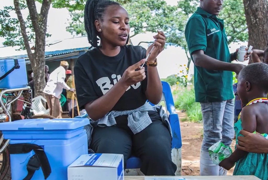 Mfanyakazi wa afya mwanamke nchini Tanzania akiandaa chanjo kwa ajili ya mtoto wakati wa kampeni ya chanjo UNICEF .