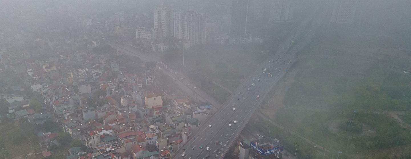 Vista aérea de Hanói, Vietnã, mostrando uma importante rodovia com tráfego em meio a uma névoa de poluição.