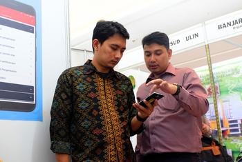 फेब्री (दाईं ओर) अब मास्टर प्रशिक्षक हैं, अपने सहकर्मी को ऐप के बारे में समझाते हुए.