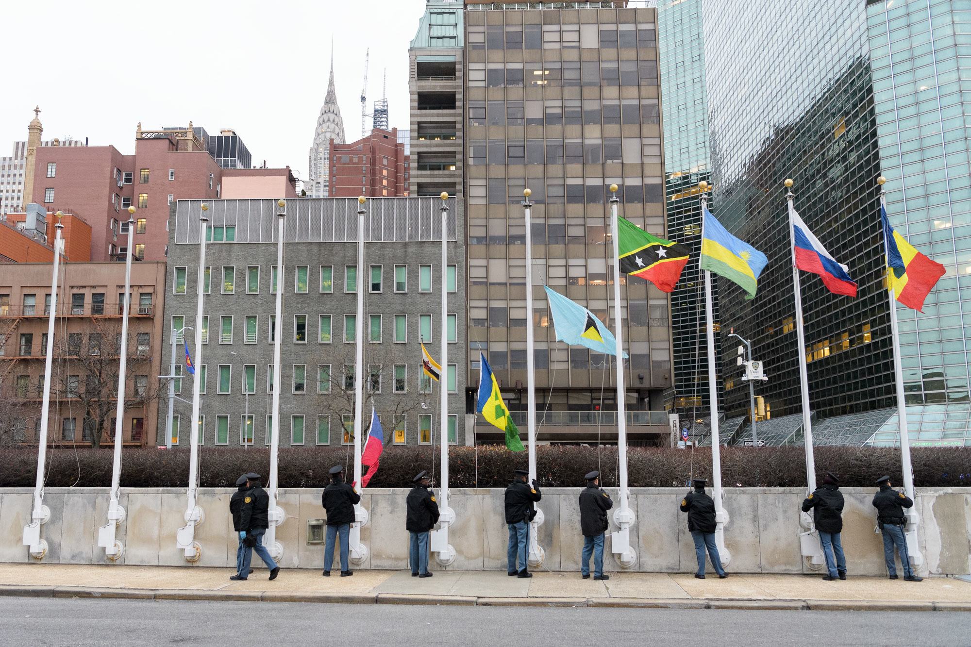 Des officiers de sécurité de ONU hissent les drapeaux des États membres de ONU au siège des ONU à New York.