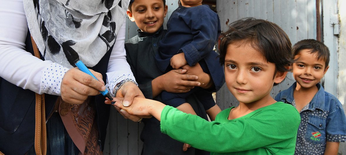 فتاة صغيرة تتلقى التلقيح ضد شلل الأطفال من العاملات الصحيات في كابول ، أفغانستان.