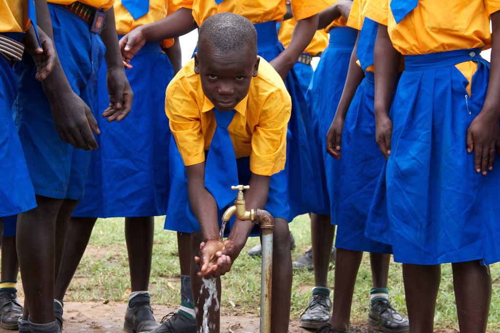 Un joven alumno de la Escuela Primaria Nakalas en Uganda se lava las manos en un grifo.